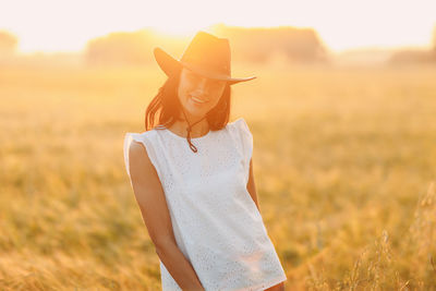 Rear view of woman wearing hat standing on field