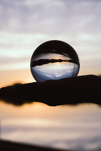 Close-up of silhouette crystal ball against sky during sunset