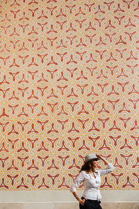 Side view of young woman casual stylish outfit holding hand on hat with ornamental wall on background