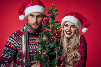 Portrait of young woman with red christmas tree during winter