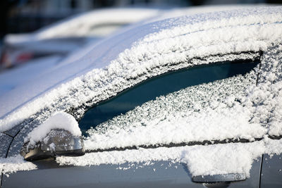 Car covered with a thin layer of fresh white snow. side view.