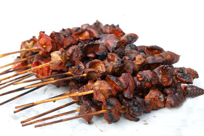 Close-up of meat on barbecue grill against white background