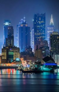 Illuminated buildings by river at night