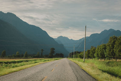 Road by mountains against sky