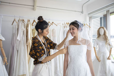 Fashion designer grooming bride at boutique