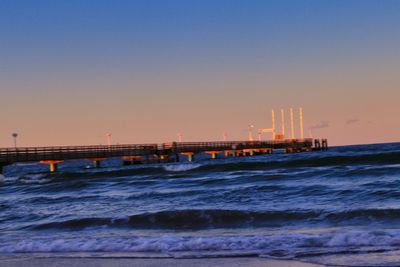 Pier over sea against clear sky during sunset