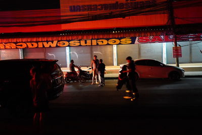 People walking on illuminated street at night