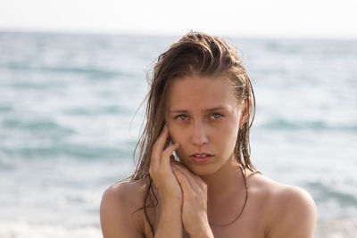 Close-up portrait of young woman standing against sea