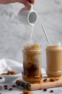 Midsection of person pouring drink in glass on table