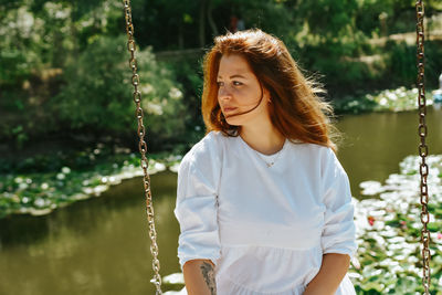 Portrait of young woman swinging at park