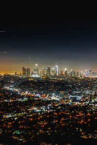 Illuminated cityscape against sky at night