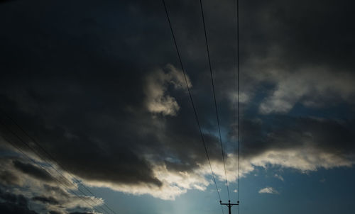 Low angle view of silhouette electricity pylon against sky