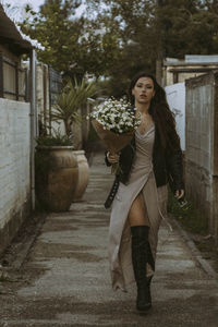 Full length of young woman standing against building