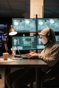 Rear view of woman using laptop at cafe