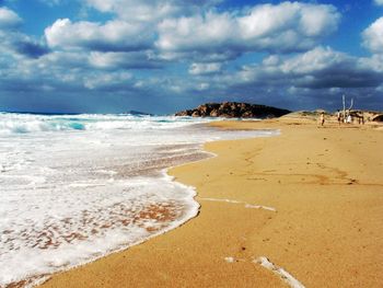 Scenic view of beach against cloudy sky