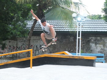 Full length of man jumping against built structure