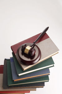 Close-up of gavel on stacked books against white background