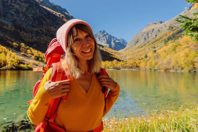 Portrait of young woman standing against lake