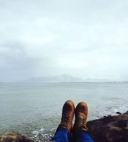 Low section of man in sea against sky