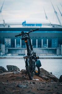 Bicycle parked on rock by sea against sky