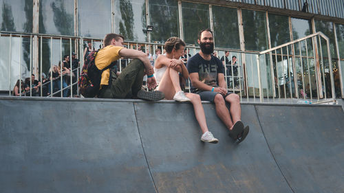 Rear view of people sitting on wall