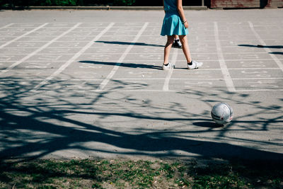 Low section of woman by soccer ball on playing field