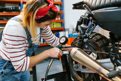 Mechanic woman checking tire air pressure of motorcycle