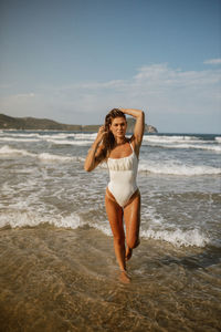 Full length of young woman standing at beach