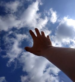 Low angle view of human hand against sky