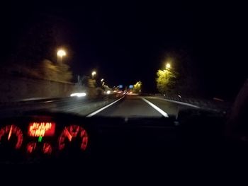 Illuminated road seen through car windshield at night