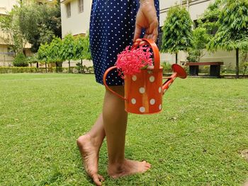 Midsection of woman holding umbrella on field