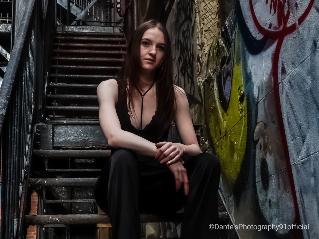 one person, graffiti, young adult, sitting, front view, real people, lifestyles, staircase, young women, casual clothing, architecture, three quarter length, leisure activity, beautiful woman, steps and staircases, beauty, hairstyle, hair, teenager, contemplation