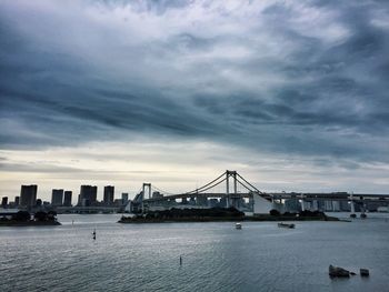 Bridge over river against cloudy sky