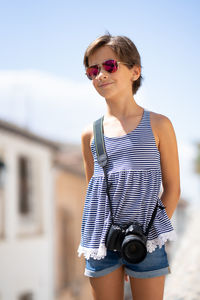 Girl wearing sunglasses while standing against sky