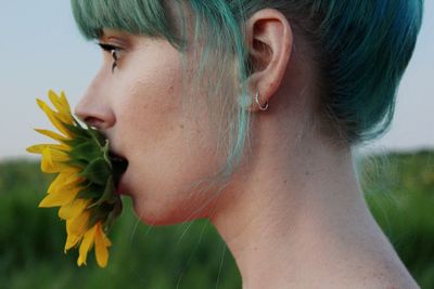 Close-up of beautiful young woman biting sunflower