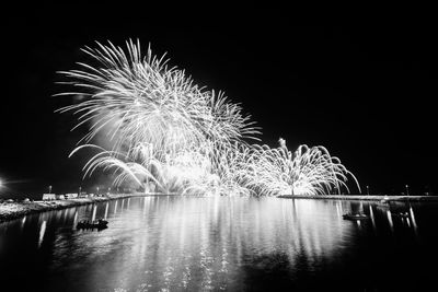 Firework display over river against sky at night