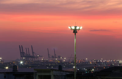 Illuminated street light against sky during sunset