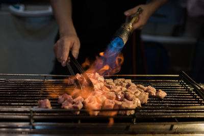 Midsection of man preparing meat on barbecue grill