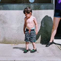 Full length of shirtless boy standing in water