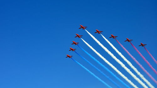 Low angle view of birds flying against clear blue sky