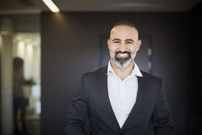 Portrait of smiling mature lawyer in formals standing at office