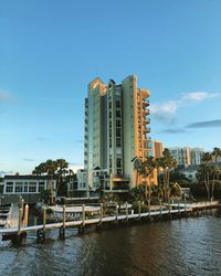 Buildings by river against sky in city