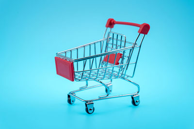 Close-up of shopping cart over blue background