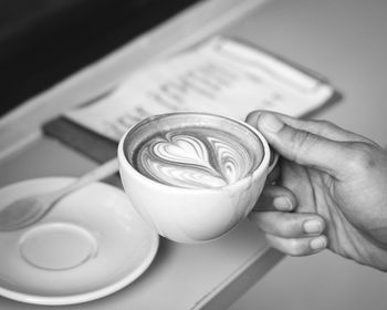Close-up of hand holding coffee cup on table