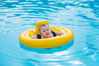 Portrait of girl with inflatable ring swimming in pool