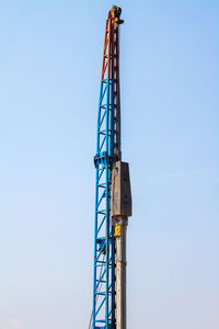 Low angle view of crane against clear blue sky