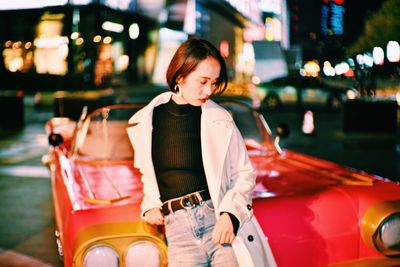 Young woman standing on street in city at night