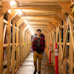 Full length portrait of smiling man standing in corridor