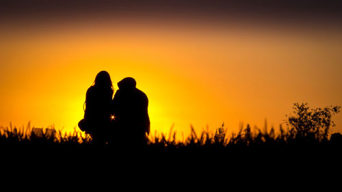 Silhouette couple against orange sky during sunset