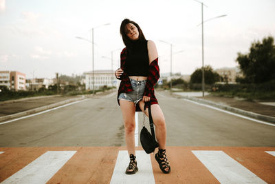 Full length of fashionable young woman on zebra crossing in city